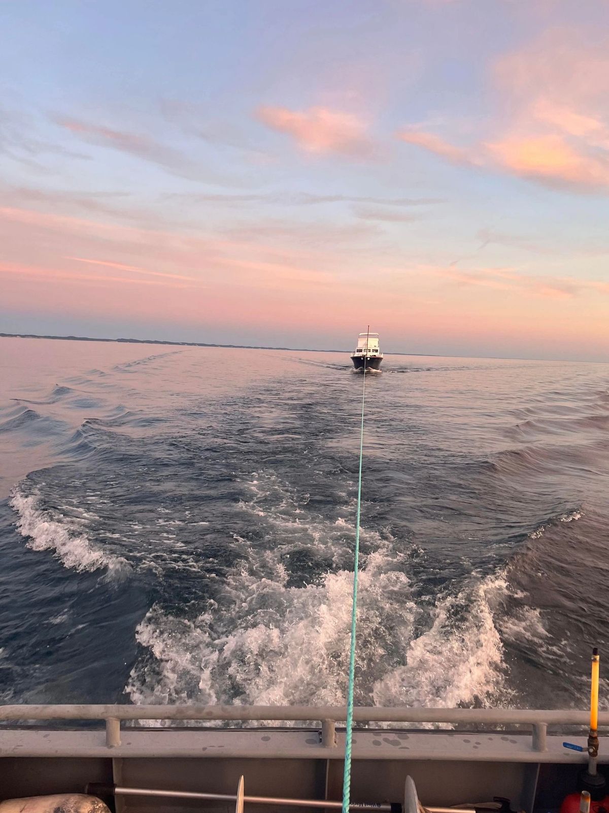 A tow boat approaching the shore at sunset during a towing operation.