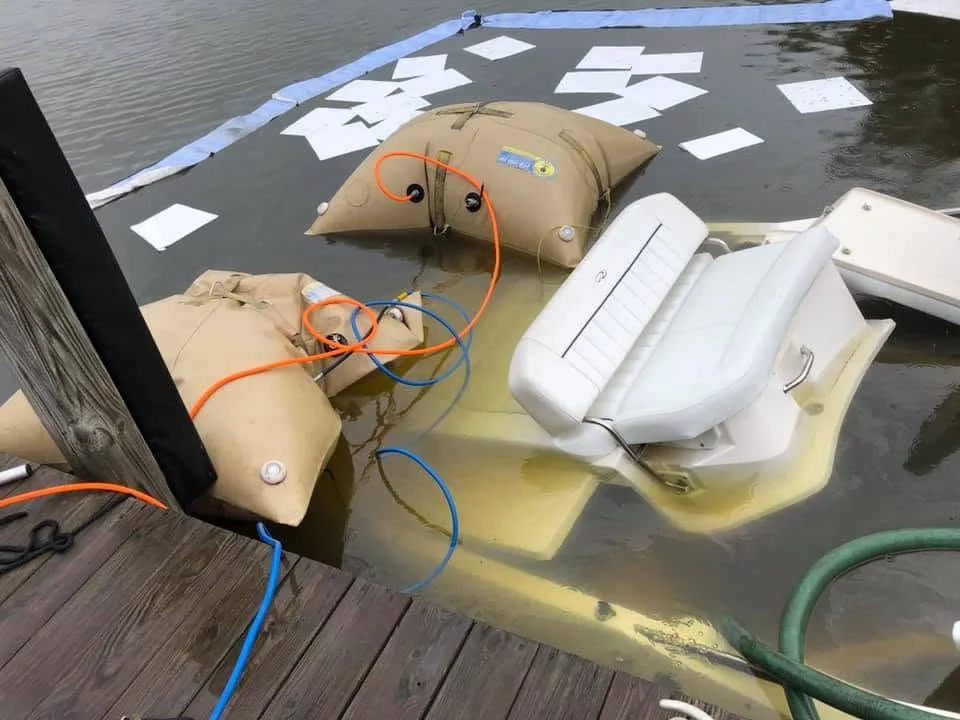 Lift bags and hoses rigged beside a partially submerged boat seat at the dock, ready for the lift.